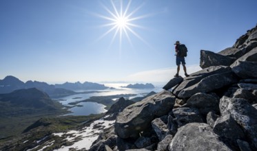 View of mountains and fjord landscape, mountaineer at the summit of Rundfjellet, Sun Star,