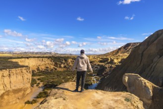 Tourist standing on cliff edge admiring the stunning landscape of bardenas reales desert in