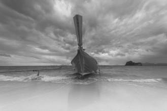 Longtail boat on the beach, dark rain clouds behind, Koh Ngai Island, Andaman Sea, Satun Province,