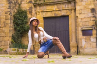 A young Latin woman with a white t-shirt, jeans and a hat enjoying the summer holidays, with a take