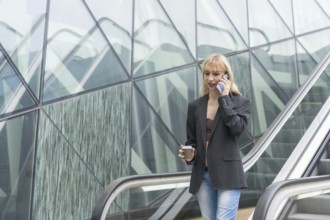 Entrepreneurial girl in business park in a modern building with escalator, young blonde in a suit