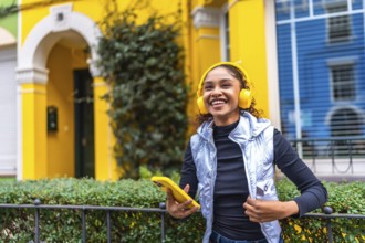 Happy african american woman smiling listening to music next to colorful houses