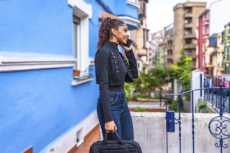 Side view photo of an african american casual businesswoman walking talking to the mobile among