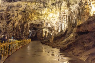 Tourists visiting the magnificent postojna cave in slovenia, riding an electric train through