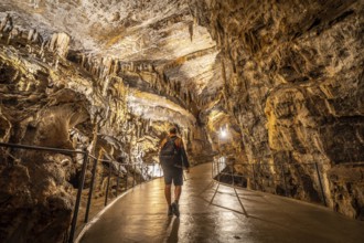 Tourist exploring postojna cave, a renowned natural wonder in slovenia, marveling at the stunning