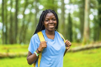 Portrait of a happy young african woman hiking through green forest