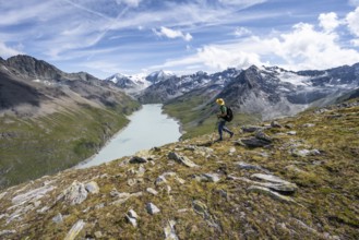 Mountaineer on the summit of Mont de la Blana, view of a blue mountain lake, Lac des Dix reservoir,