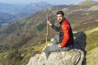 A man sitting on a rock at the top of Mount Ernio or Hernio in Gipuzkoa at sunset, Basque Country