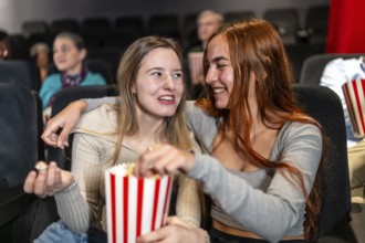 Two female friends enjoying a movie night, sharing popcorn and laughs, creating a joyful and