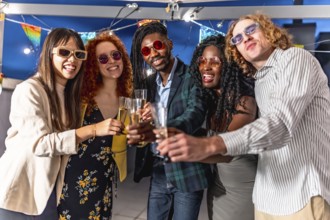 Elegant multiracial friends toasting with champagne together looking at camera at night party in a