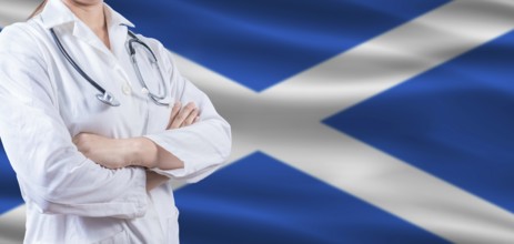 Doctor with crossed arms on Scottish flag. Scotland health and care concept. Female doctor on