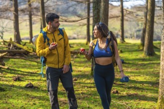 Hikers enjoying a healthy snack of apples while walking through a sunny forest during their outdoor