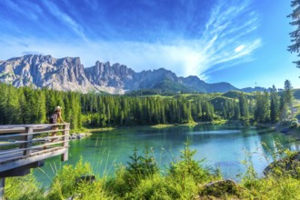 Female tourist admiring the stunning turquoise waters of lake carezza with the latemar mountain