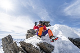 Happy mountaineer with ice axes and crampons on the summit of Piz Grialetsch in winter, Graubünden