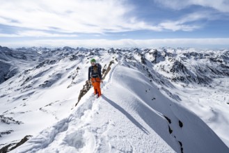 Mountaineer on a narrow mountain ridge in winter, summit of Piz Grialetsch, view of mountain