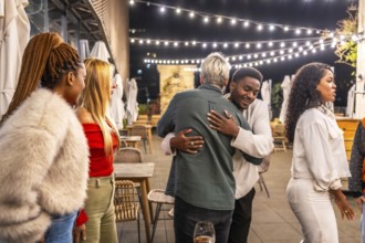 Multi-ethnic friends hugging while arriving in a meeting in a night bar