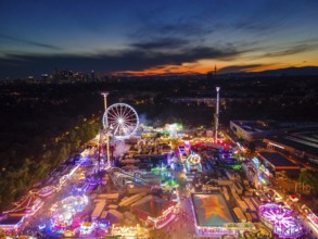 The lights of the Dippemess in Frankfurt am Main glow after sunset. Aerial view, ice rink,