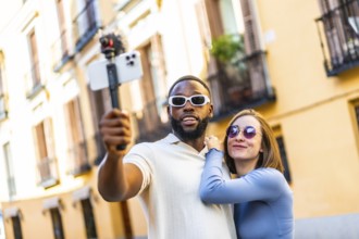 Multi-ethnic couple influencer vlogging from a travel destination standing in the city street