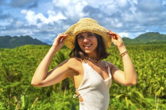 Young woman enjoying a sunny day in a coconut plantation in siargao island, philippines, holding