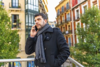 Elegant caucasian adult man in winter clothes talking to the phone in the city