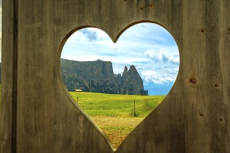 Breathtaking view of the italian dolomites, seen through a heart shaped opening in a wooden fence,