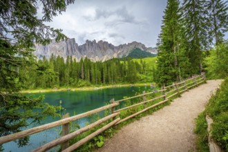 Emerald green water reflecting the majestic dolomites under a cloudy summer sky in south tyrol,