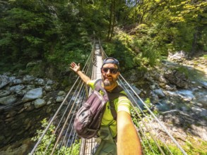 Hiker taking selfie while crossing hanging bridge over tolmin gorge in triglav national park,