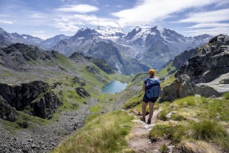 Hiker on hiking trail, mountain lake Lac de Louvie with glaciated summit of the Grand Combin, Val
