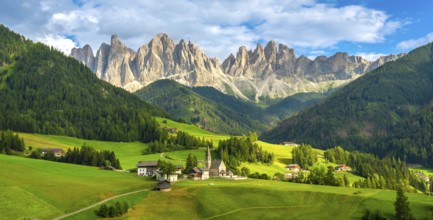 Green meadows, traditional houses, and the iconic santa maddalena church create a picturesque scene
