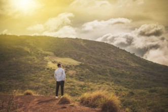 Rear view of a lonely man on top of a hill looking at the horizon. Back view of lonely man on a