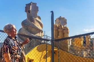 Senior tourist admiring the whimsical chimneys and vibrant architecture of casa mila, a unesco