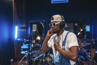 Young, stylish male artist passionately recording a song in a professional music studio, surrounded