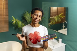 Portrait of a latin young gay smiling man making up at home