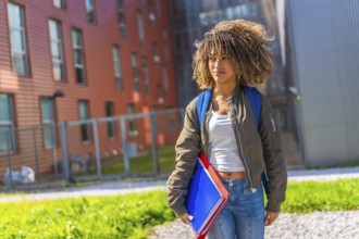 Confident latin young woman standing in the university campus looking away holding notebooks,
