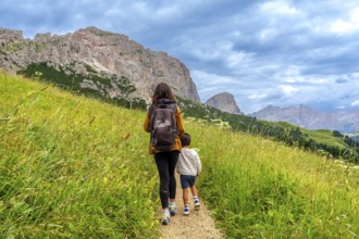 Mother and son walking on a path surrounded by lush green grass, enjoying the breathtaking view of