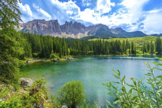 Emerald waters of lake carezza reflecting latemar mountain range in the dolomites, italy, on a