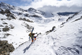 Mountaineer with skis climbing up a steep snow slope to the fork Porta d'Es-cha, ski tour Bündner
