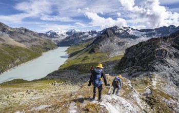 Two mountaineers on the summit of Mont de la Blana, view of a blue mountain lake, Lac des Dix