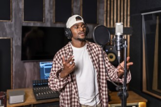 Young artist wearing headphones and singing into microphone while recording a song in professional