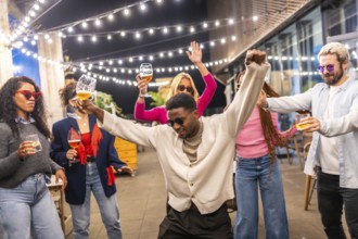 African cool man dancing next to multi-ethnic friends at outdoors party at night