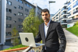 Portrait of a mature adult caucasian elegant and confident businessman using laptop standing in the