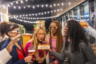 Blonde woman blowing candles of birthday cake celebrating party with friends at night in the