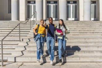 Three multi-ethnic university students walking down stairs recording online video blog with