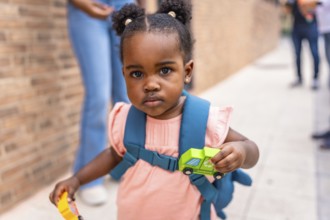 Close-up of an african cute schoolgirl carrying card toys in the street