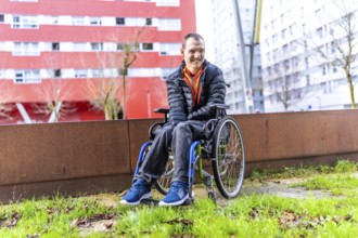 Young man with disability smiling in his wheelchair enjoying a day out in an urban park, promoting