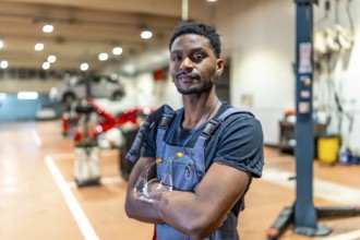 Young african american mechanic standing with crossed arms and protective eyewear in a car repair