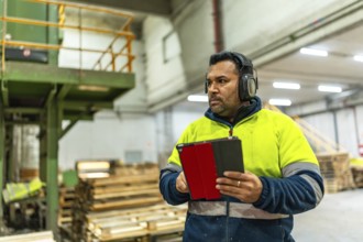 Man caucasian adult worker doing inventory using digital tablet in a recycling plant full of