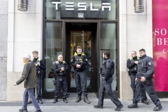 Berlin, Germany - 5 April 2025: Police guard the entrance to a Tesla shop as people demonstrate