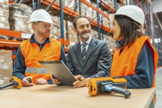 Manager holding a clipboard, engaging in discussion with warehouse workers about improving