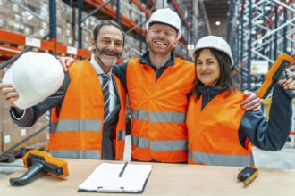 Warehouse workers and their manager are smiling and hugging each other, celebrating a successful